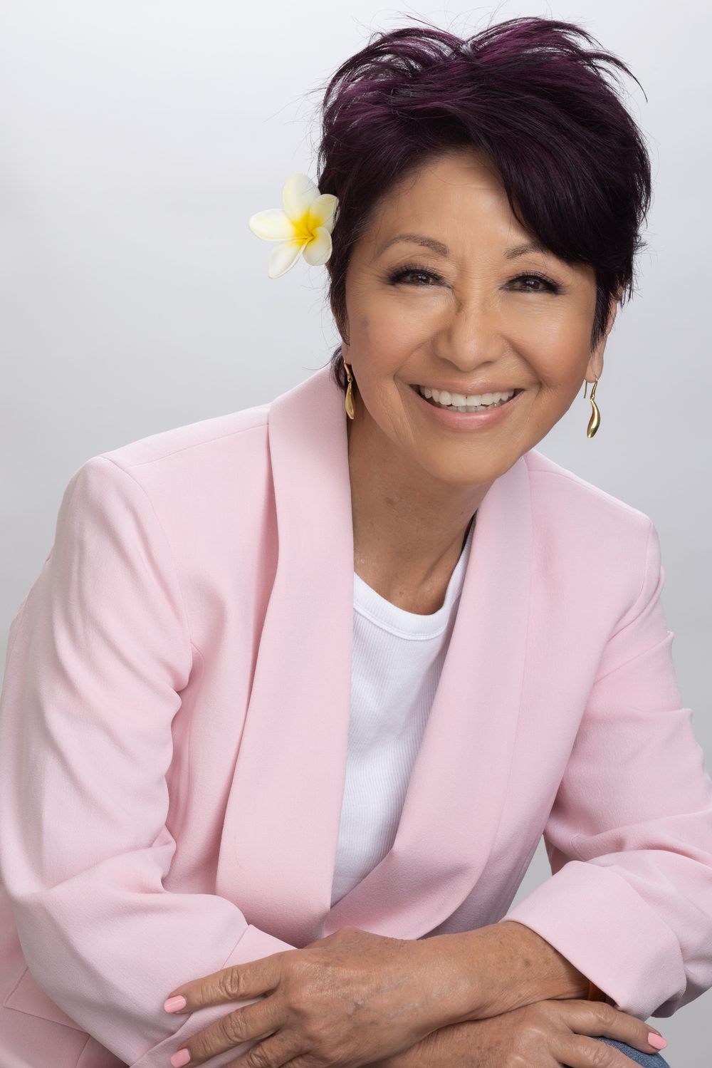 Olelo paʻa Ogawa in a pink blazer with a plumeria in her hair