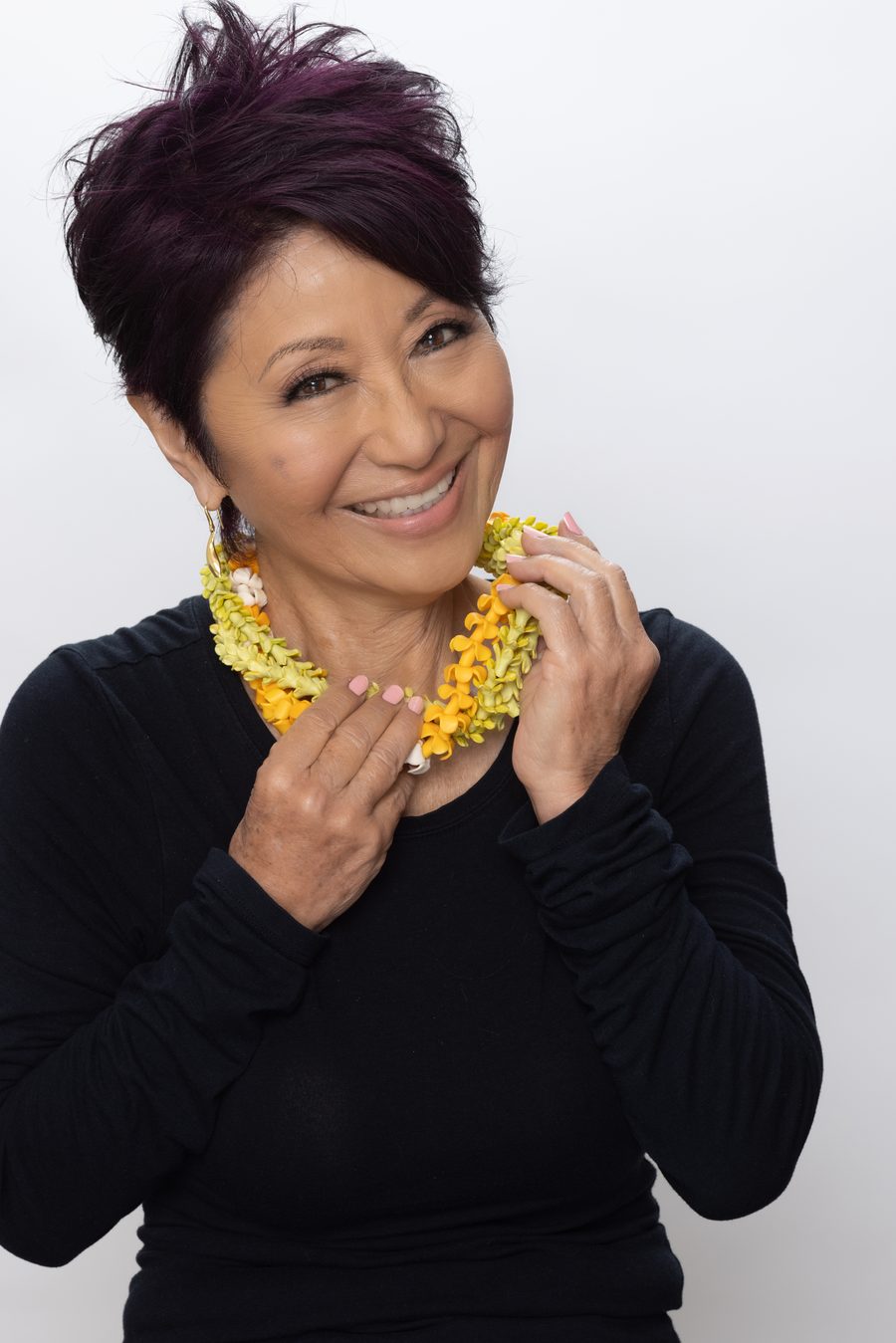 Olelo paʻa Ogawa laughing joyfully, holding her yellow and orange lei